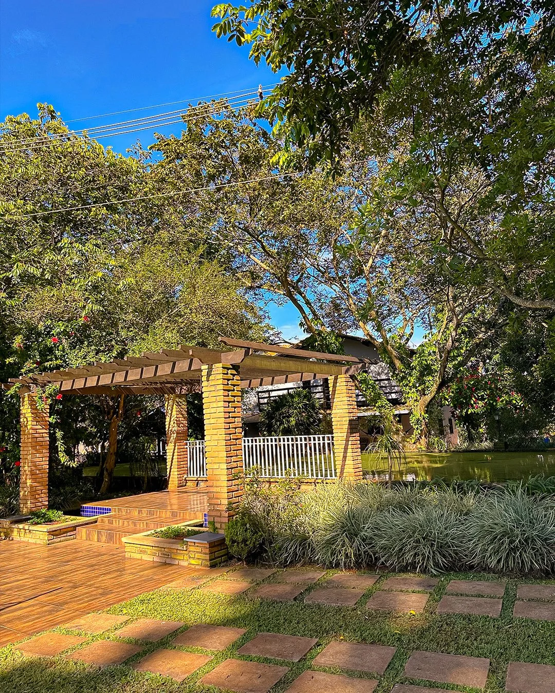 Pergolado de tijolos com deck de madeira à beira do lago