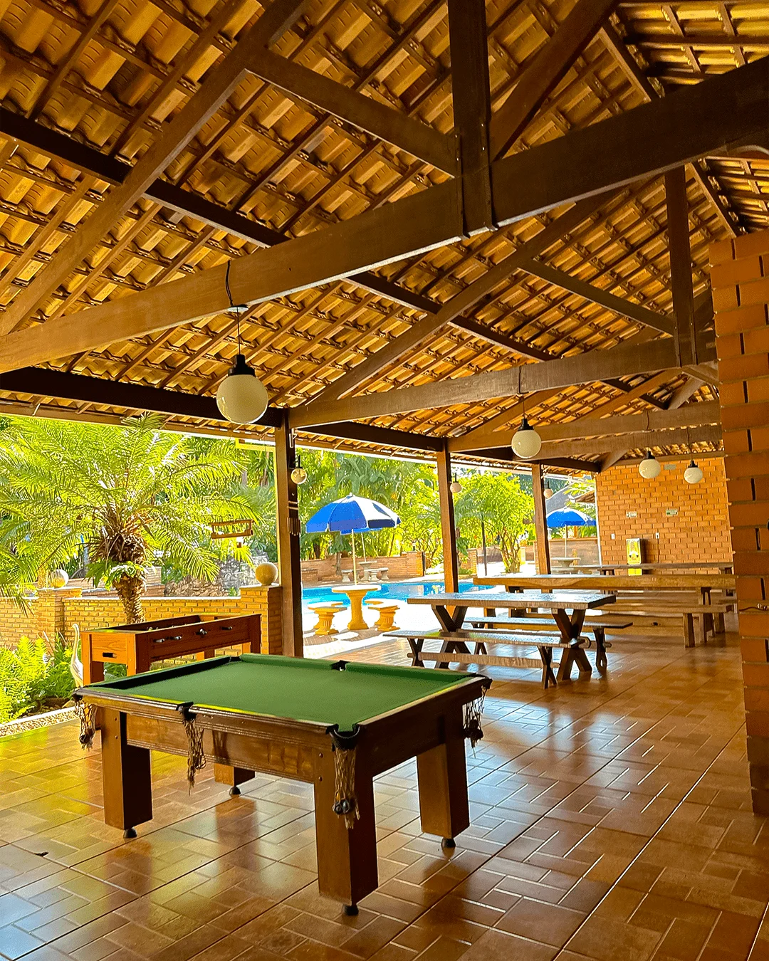 Área de lazer coberta com mesa de sinuca e vista para a piscina